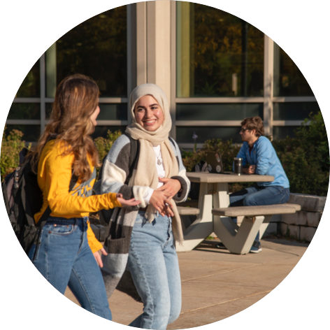 Two girls walking, one wearing a headscarf.