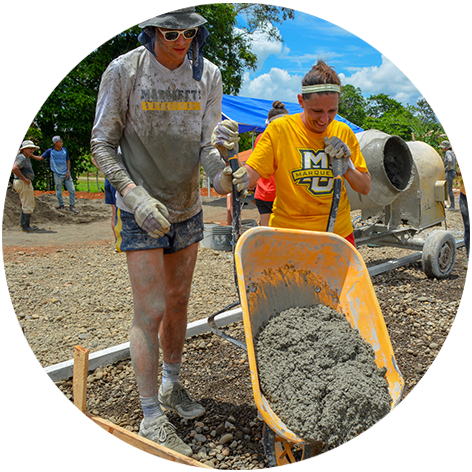 Students pouring dirt from a wheelbarrow